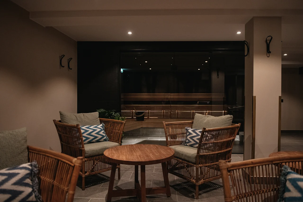 En varm og innbydende avslapningslounge med komfortable sitteplasser og utsikt inn i et rolig trepanelkledd rom.