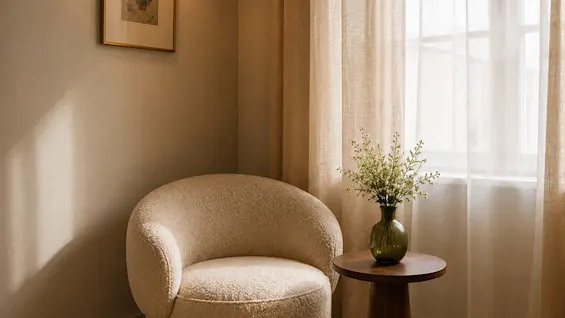 En mysig hörna med ljus fåtölj, sidobord med blommor, fönster med skira gardiner. Våra rum tar form – visualiseringar, ej fotografier.