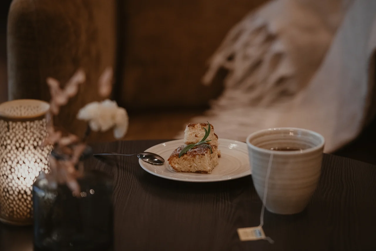 En hyggelig scene med et stykke kage og en kop te på et træbord, der antyder en afslappende pause.