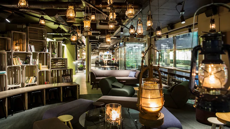 Cozy interior lounge with hanging lanterns, plush seating, and bookshelves providing an inviting ambiance for relaxation or casual meetings.