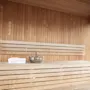 Rauhallinen saunahuone, jossa on vaaleat puupenkit ja seinät, kulho ja pyyhe valmiina virkistävään istuntoon.