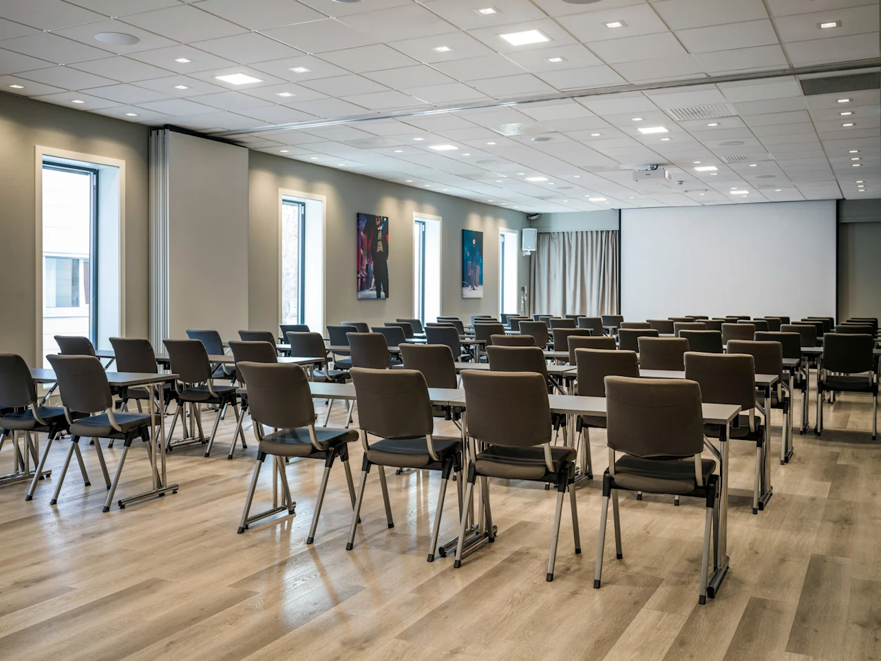 A spacious, modern conference room with rows of tables and chairs, ready for a meeting or presentation.