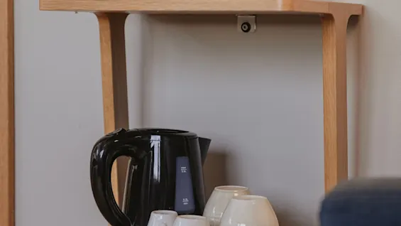 Home Hotel Wellington: En hyggelig drikkestation med kaffemaskine, elkedel og diverse kopper og glas, klar til brug.