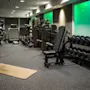A well-equipped gym with various exercise machines, a rack of dumbbells, and a yoga mat on the floor, ready for a workout.