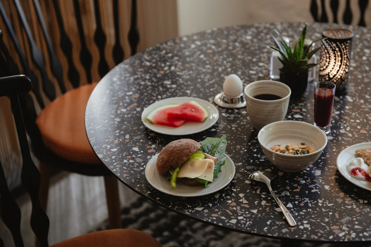 Herkullinen aamiaistarjoilu pilkullisella pöydällä, sisältäen voileivän, hedelmiä, kahvia ja muroja, valmiina nautittavaksi.