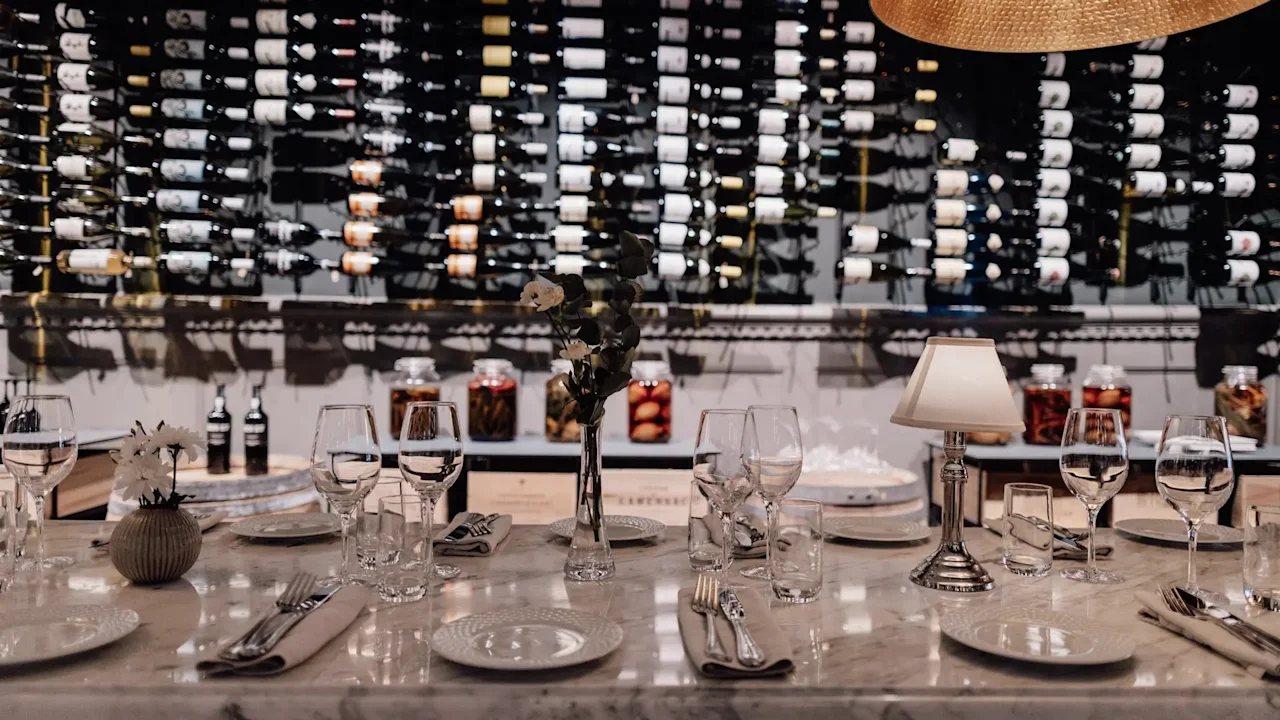 Jørgensens Hotel – Restaurant Eydes – Vinbar. Et elegant dekket bord for et måltid, med en stor vinsamling.