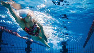Kvinna simmar längder i bassäng.
