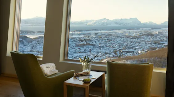 Et komfortabelt siddeområde med en fantastisk udsigt over en snedækket by, et stort vandområde og fjerne bjerge.