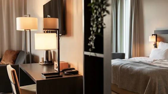 Et hyggeligt hotelværelse med skrivebord og en behagelig seng, perfekt til arbejde og afslapning.