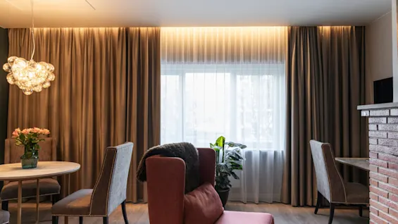 A warm and inviting lounge area at Home Hotel Grand Bodø, featuring comfortable seating, a small table with flowers, and soft lighting.