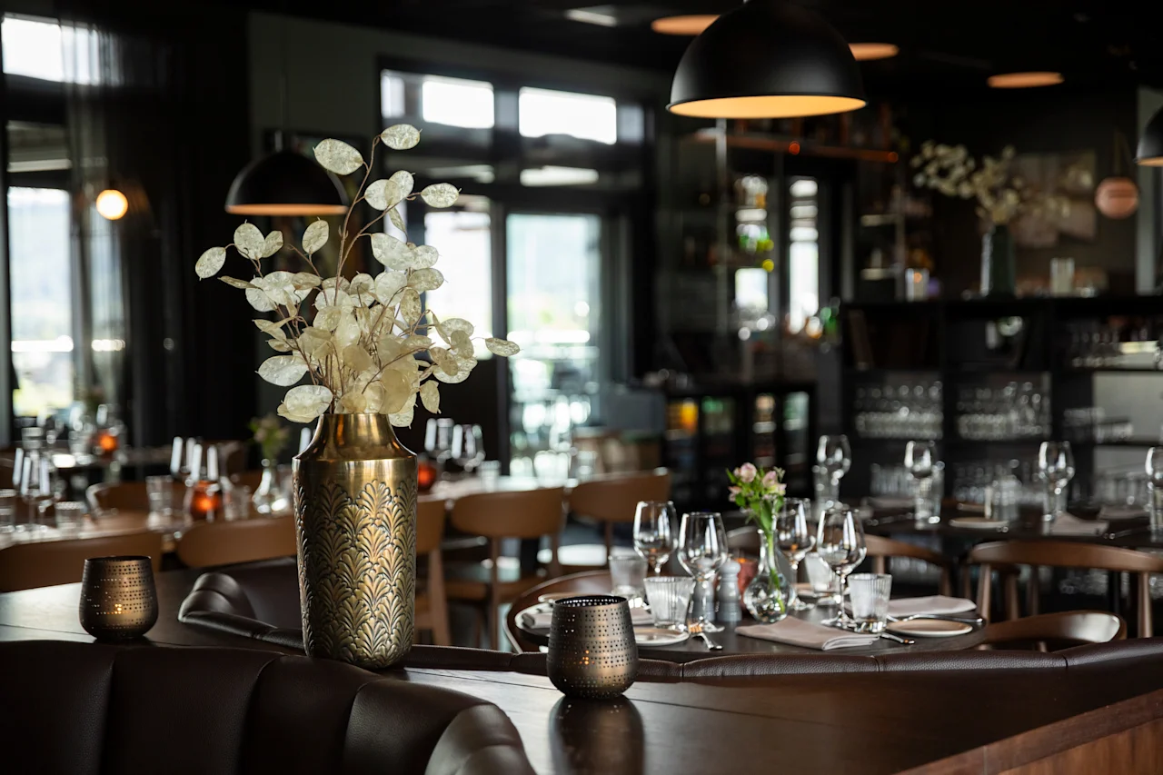 Et koselig restaurantinteriør med dekkede bord, elegant innredning og varm belysning, klart for gjester.
