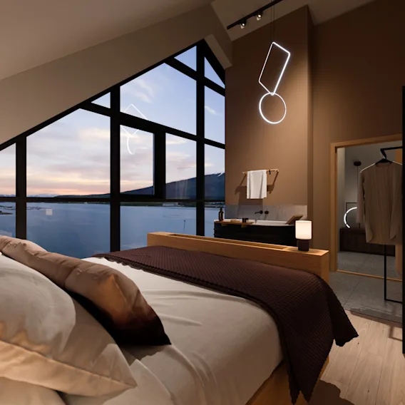Modernt hotellrum med stor fönsterutsikt över sjö och berg i skymningen, med en bekväm säng.
