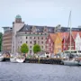 Naturskøn havn med historiske farverige træhuse og både fortøjet langs kajen.