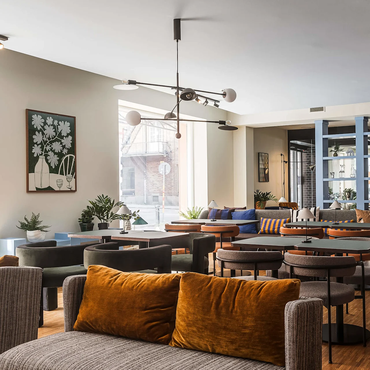 En modern lounge med stilfulla soffor, stolar och bord, varmbelysning och färggranna prydnadskuddar, mot en fond av neutrala och kraftfulla väggfärger.