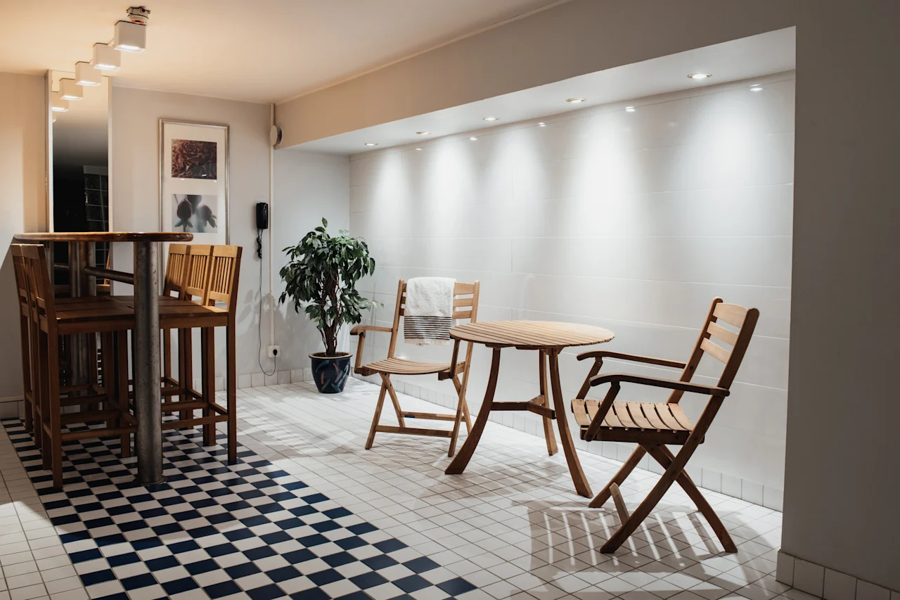 Home Hotel Kung Oscar: A cozy indoor seating area with a high bar table and stools, and a separate wooden table with chairs.