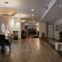 A spacious and inviting hotel lobby with a grand piano, comfortable seating, and a view into a bustling restaurant area.