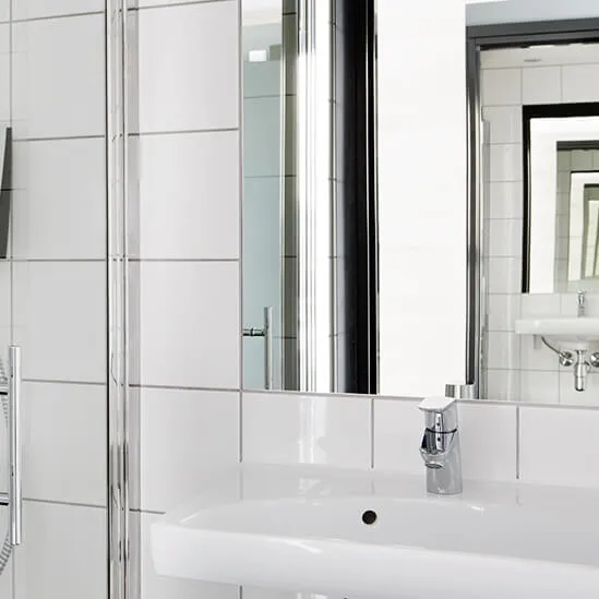 A modern bathroom corner with a glass shower enclosure and a white sink with a mirror.