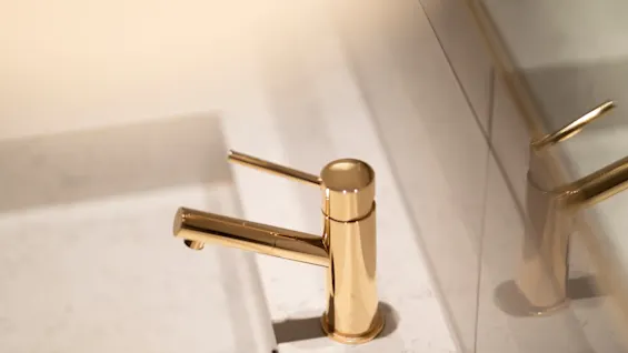 A sleek golden faucet in a modern bathroom at Home Hotel Grand Bodø.