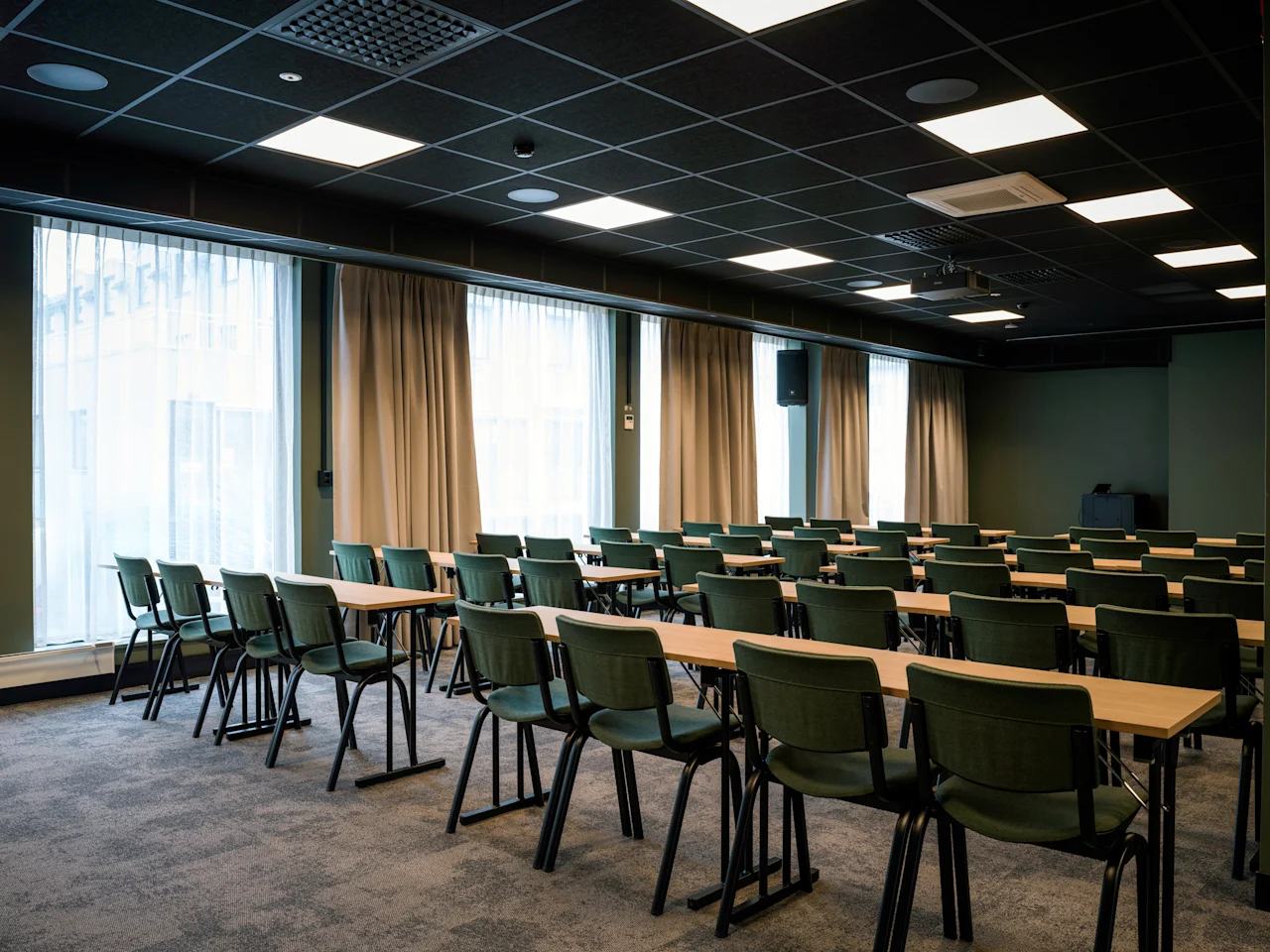 A spacious conference room with rows of tables and chairs, ready for a meeting or presentation.