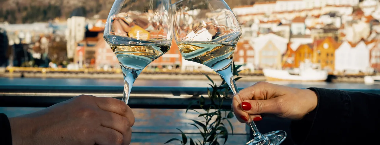 Two wine glasses clinking at a restaurant in Bergen. 