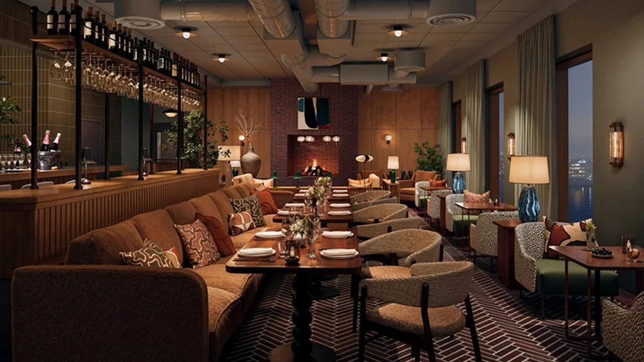 Mysig restaurang med mjuka sittplatser och dukade bord; vinglas uppradade vid en träbar. Mjuk belysning skapar en varm atmosfär, med en tegelspis som fokuspunkt.
