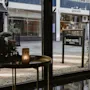 Näkymä rakennuksen sisältä kadulle, jossa on kyltti HOME HOTEL CARDINAL. Pöydällä on sytytetty kynttilä.