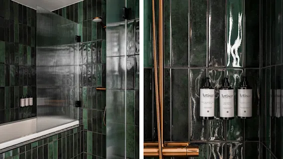 Hernö Gin Hotel badeværelse med mørkegrønne fliser, bruser, badekar og vægmonteret Hair & Body Wash, Shampoo, Balsam.