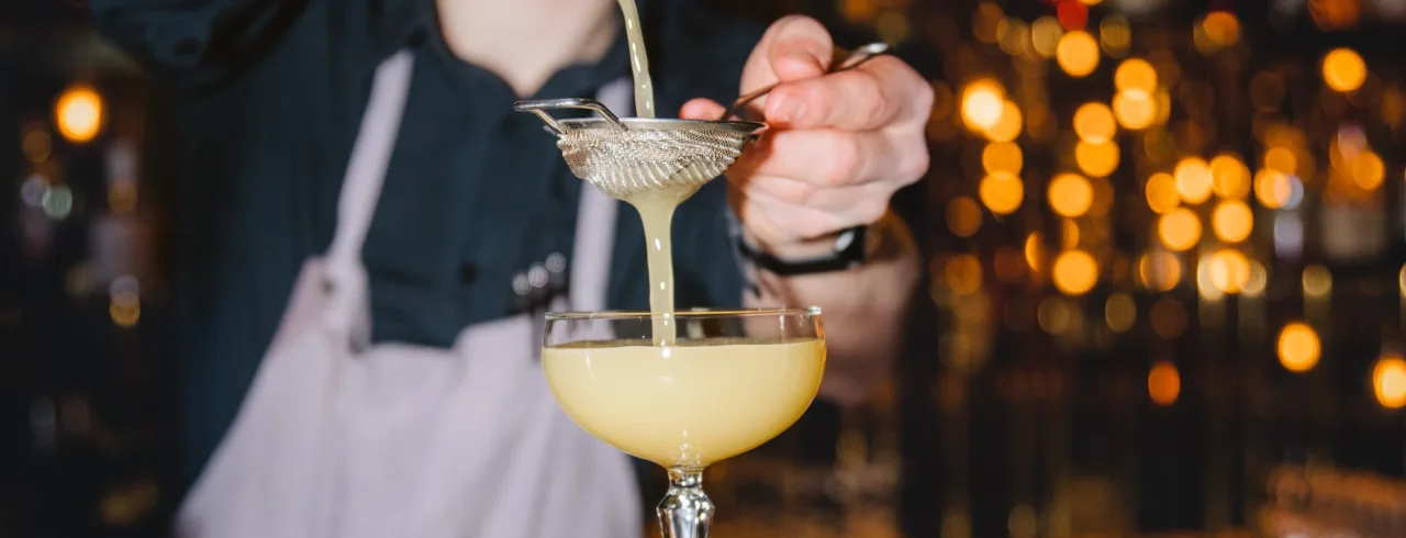 A bartender pouring a yellow drink in a cocktail glas at Kava Cocktail.