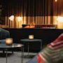 Et hyggeligt loungeområde med en lang pejs, der kaster et varmt skær. Stearinlys på små borde bidrager til den indbydende atmosfære.