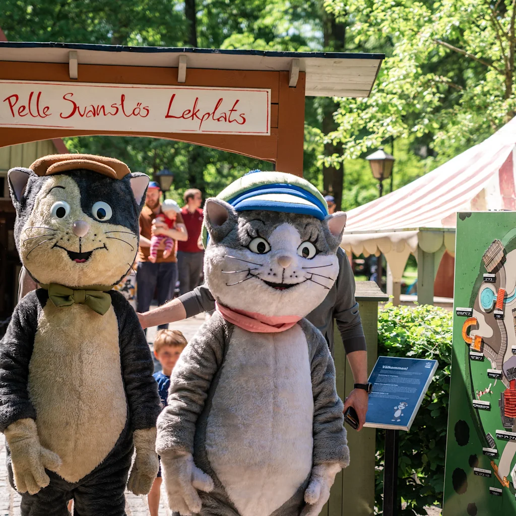 Kaksi kissamaskottia seisoo Pelle Svanslos Lekplatsin sisäänkäynnillä, leikkisässä puistossa Uppsalassa.