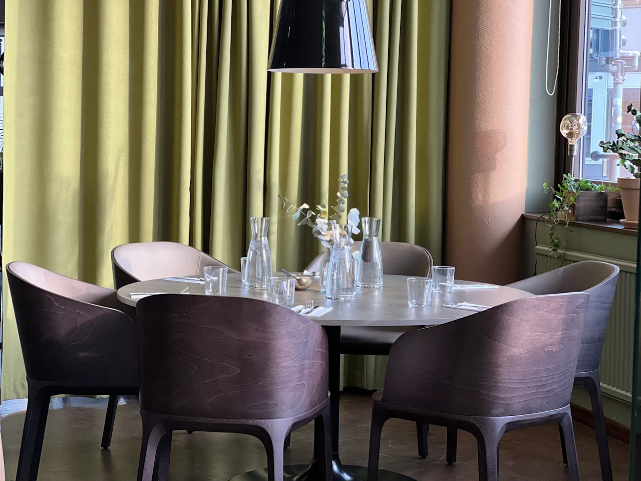 Ett vackert dukat runt matbord med stolar och gröna gardiner, redo för gäster på Quality Hotel Royal Corner.