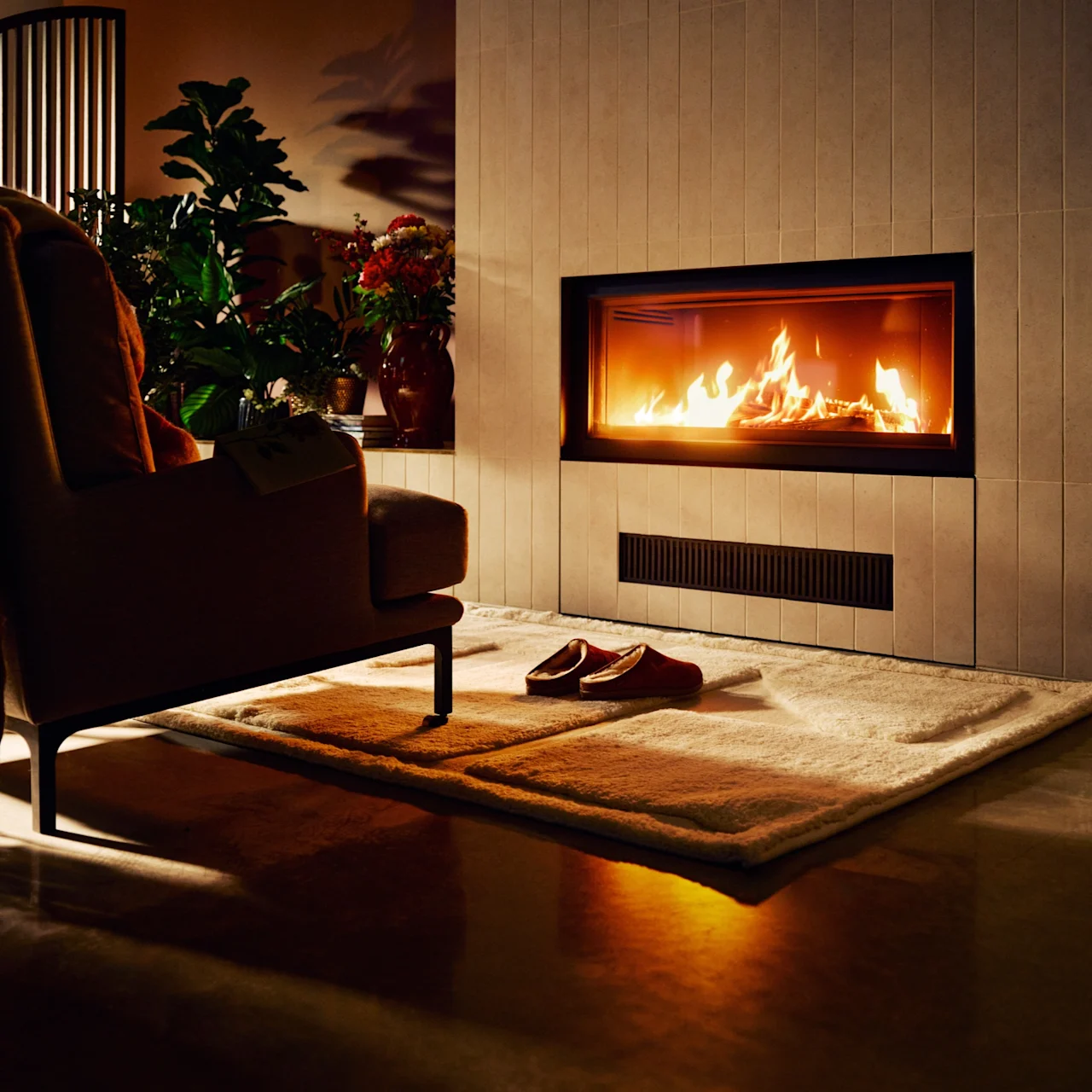 Koselig oppholdsrom med varm peis, innbydende lenestol med teppe og tøfler på mykt teppe, perfekt for avslapning.