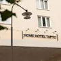 The exterior of a building with a sign that reads HOME HOTEL TAPTO, with a street lamp in the foreground.
