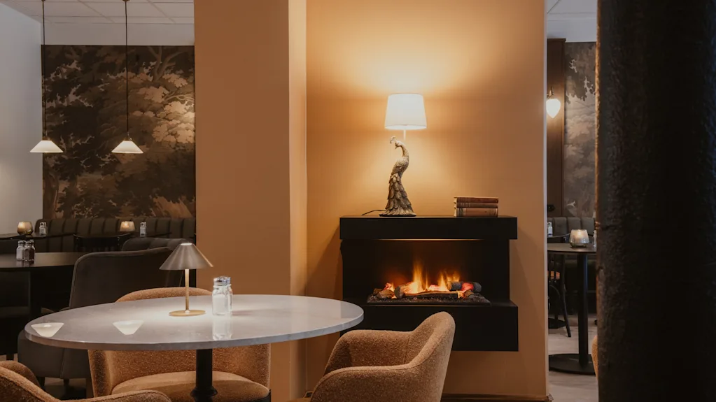 Cozy lounge area at Home Hotel Baltzar with a warm fireplace, comfortable seating, and elegant decor.