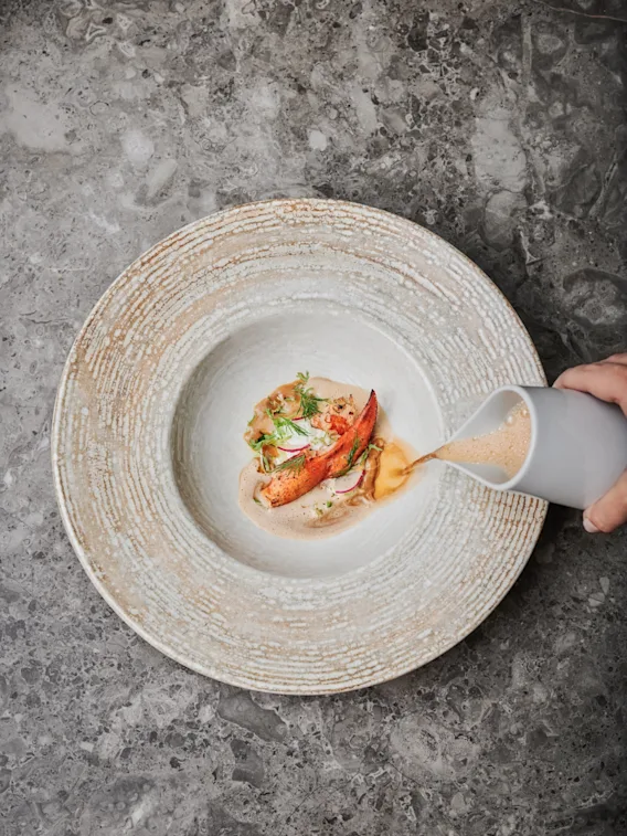 Krämig soppa hälls över en elegant hummerrätt