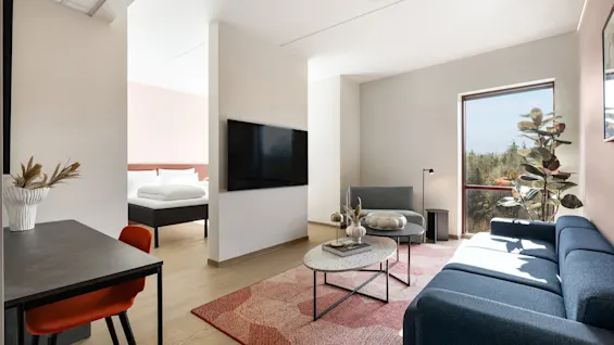 En innbydende hotellsuite med distinkte stue-, spise- og soveområder, designet for komfort og avslapning.