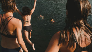 Jenter hopper ut i vannet på sommeren.