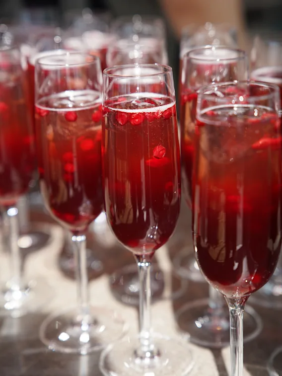 Nærbilde av flere champagneglass fylt med en musserende rød drikke og bær, klare for en feiring.