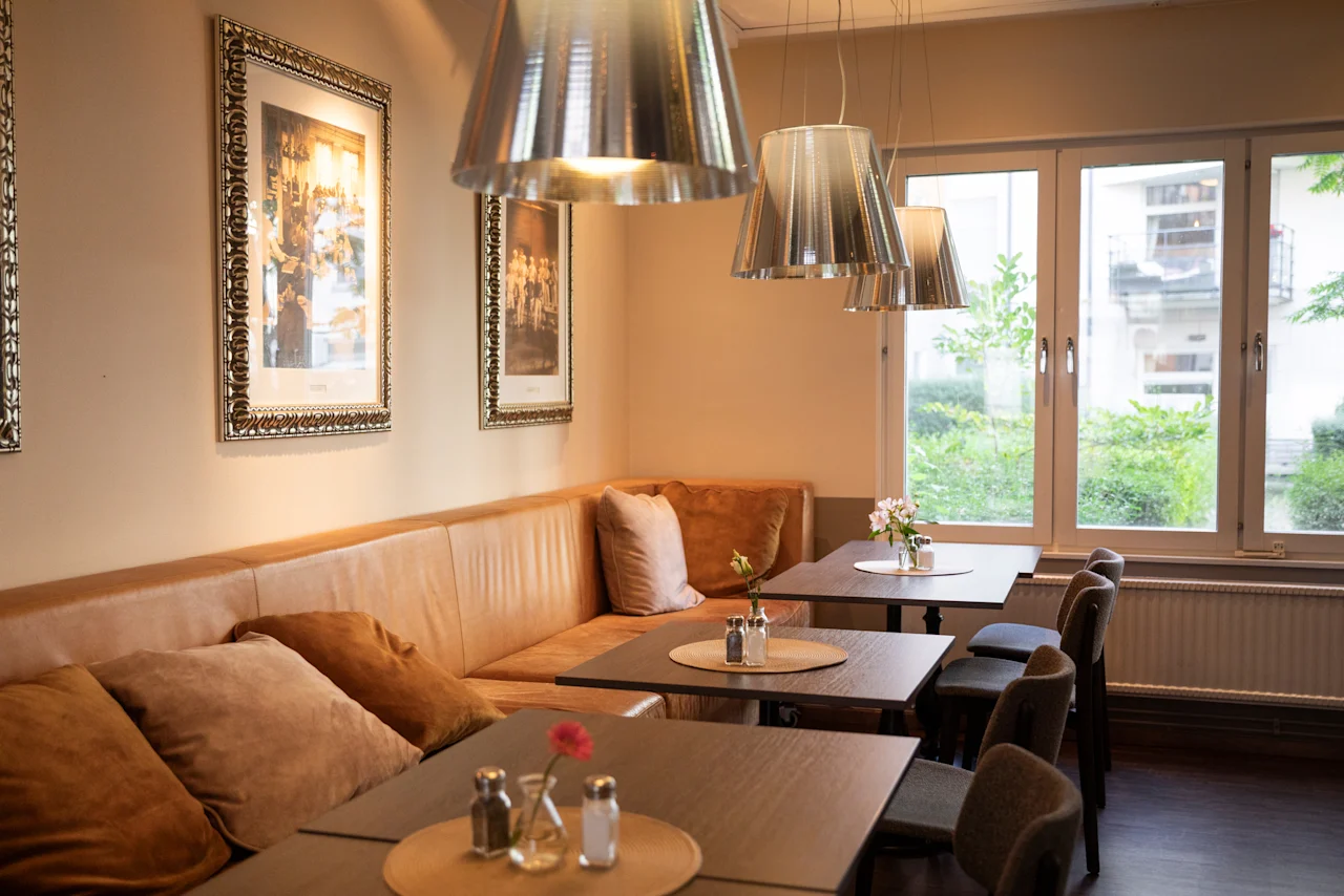 En inbjudande restaurang eller kafé med bekväma bås, matbord, modern belysning och utsikt över naturen utanför.