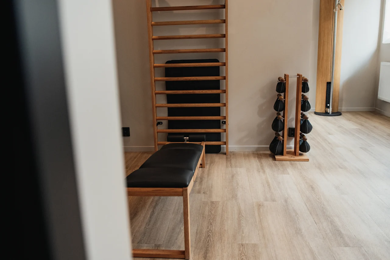 A clean and modern fitness room at Home Hotel Uppsala with an exercise bench, wall ladder, and weighted bags for a workout.