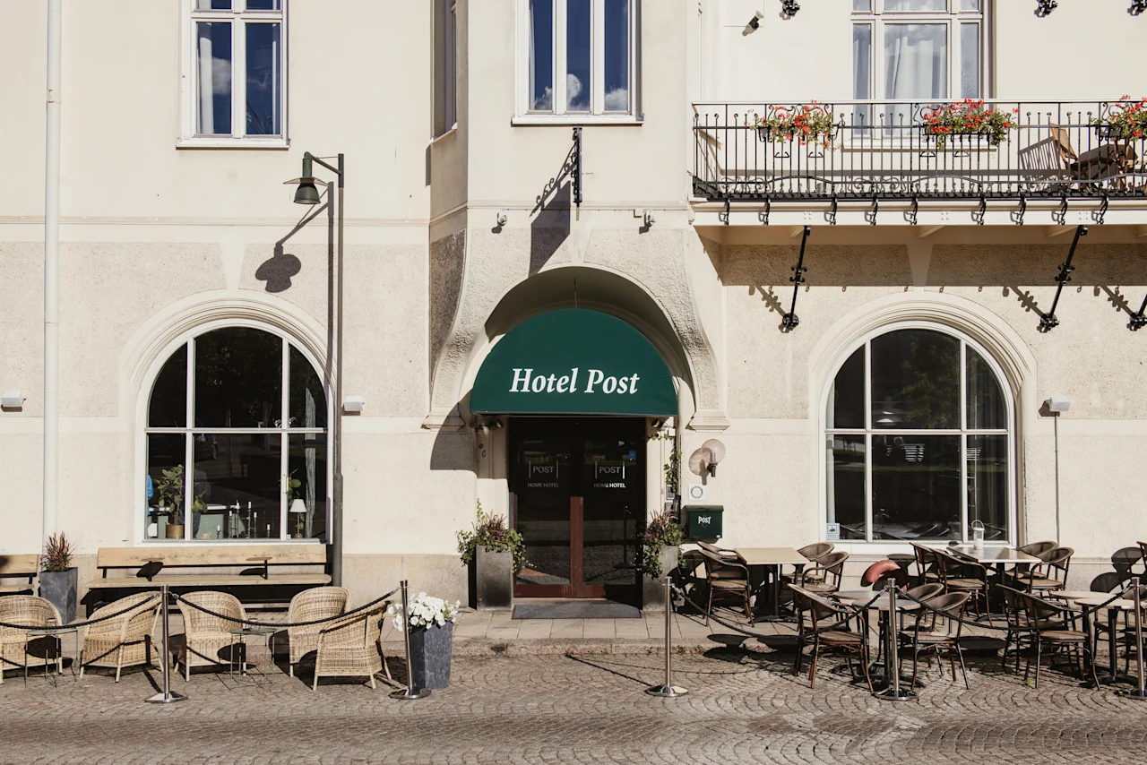 Hotellets exteriör med en grön markis där det står Hotel Post, med uteserveringar en solig dag.