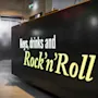 A black counter displays the text "Keys, drinks and Rock’n’Roll" in a modern lobby, with elevators in the background.