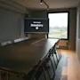 Et moderne konferanserom på Stopover Hotel Falkenberg med en stor skjerm som viser "MORE TO EXPLORE" og et langt bord med stoler.