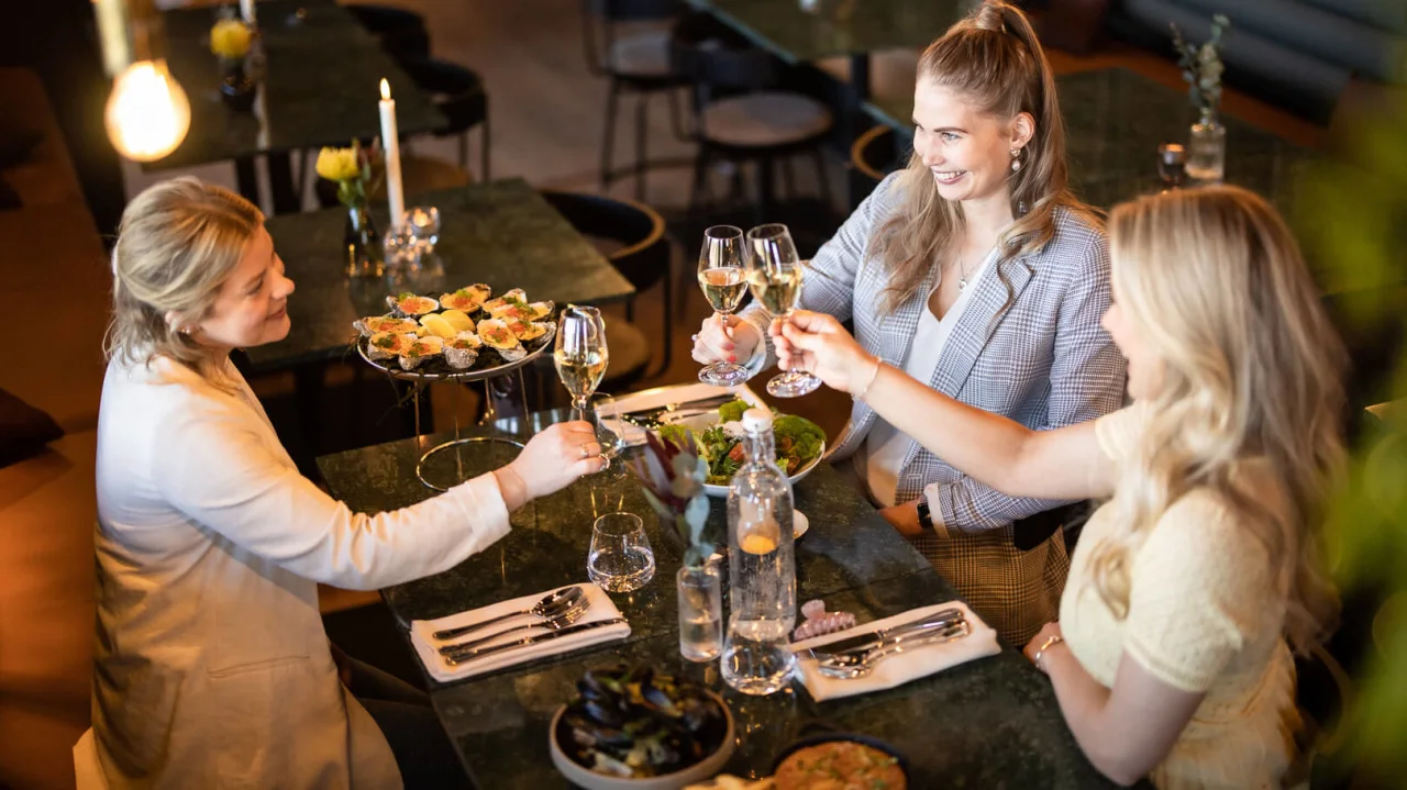  three women toast at lunch in a restaurant