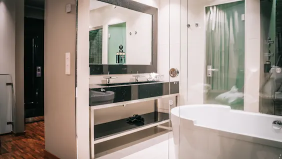 Ett stilrent och rymligt badrum med dubbelhandfat, en stor spegel och ett modernt badkar, för en uppfriskande upplevelse.