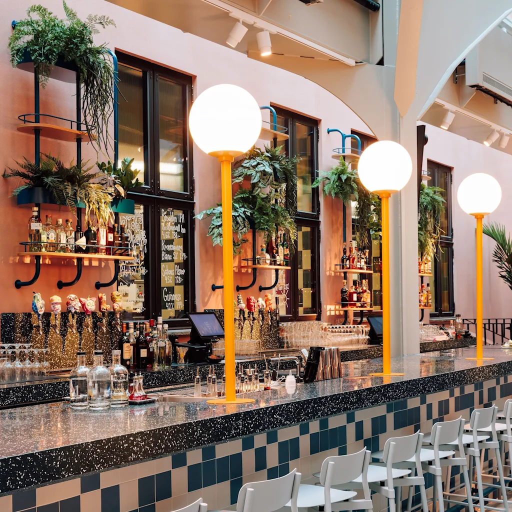 En livlig bar med disk, barkrakker, drikke, planter og sterke lys.