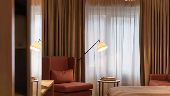 A cozy corner in a hotel room at Home Hotel Grand Bodø, featuring a comfortable armchair, a floor lamp, and soft lighting.