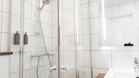 Valoisa, moderni kylpyhuone Home Hotel Victoriassa, jossa on kaakeloitu suihku, lasiseinä ja pesuallas.