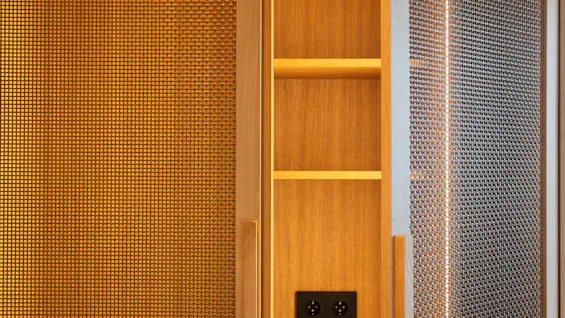 Et moderne træskab med oplyste netlåger, en let åben, der afslører hylder og stikkontakter indeni.