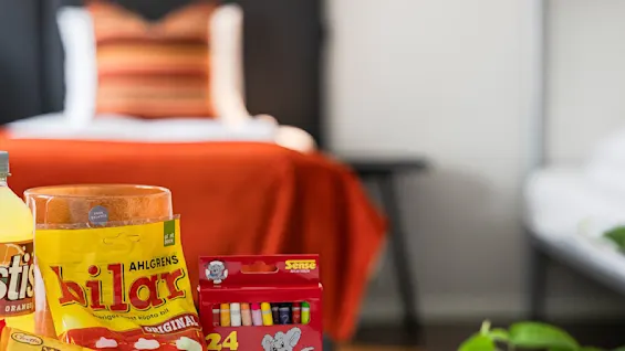 Et koselig rom med snacks, fargestifter og fargeleggingsark på et bord. Køyesenger og et mykt pledd gir en innbydende stemning for avslapning og kreative aktiviteter.